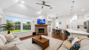 A spacious living room with a fireplace, a dining area, and a kitchen. -     Corporate Friendly Frisco Home Fast WiFi Office Near Major Headquarters (Frisco)