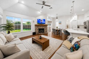 A spacious living room with a fireplace, a dining area, and a kitchen. -     Corporate Friendly Frisco Home Fast WiFi Office Near Major Headquarters (Frisco)