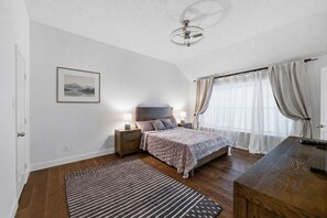 A bedroom with a bed, bedside tables, a nightstand, a ceiling fan, a window with curtains, and a framed picture on the wall. -     Corporate Friendly Frisco Home Fast WiFi Office Near Major Headquarters (Frisco)