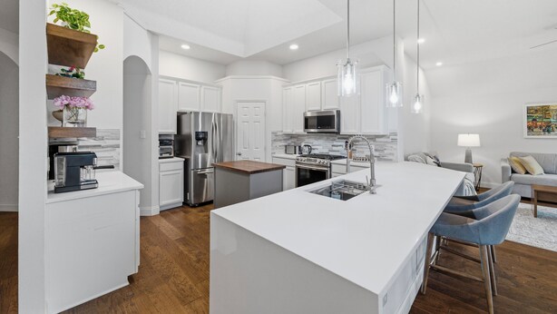 A modern kitchen with white cabinetry, stainless steel appliances, and a central island with bar stools. -     Corporate Friendly Frisco Home Fast WiFi Office Near Major Headquarters (Frisco)