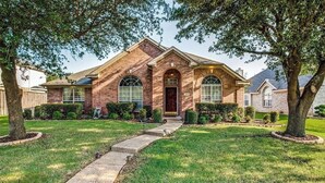 A brick house with a front entrance, a driveway, and a well-maintained lawn. -     Corporate Friendly Frisco Home Fast WiFi Office Near Major Headquarters (Frisco)