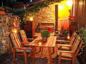 A patio with wooden furniture, a stone wall, and a wooden door. - Herlíkovice by Interhome (Vrchlabi)