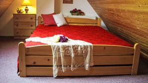 Un lit en bois dans une pièce dont le plafond est en pente, une table de chevet avec une lampe et un tableau accroché au mur.