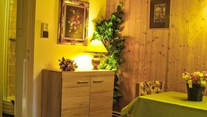 Une pièce avec un meuble en bois, une table verte et une plante fixée au mur.