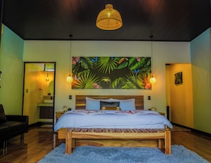 A bedroom with a bed, a wooden headboard, a tropical-themed wall mural, and a hanging light fixture. - Tree House La Fortuna w/Jacuzzi (La Fortuna)
