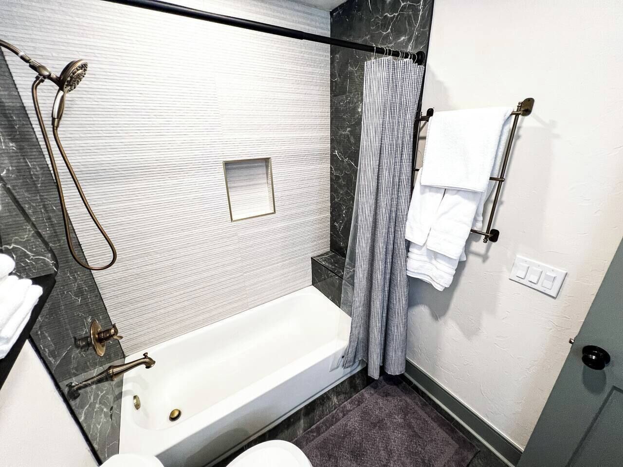 A modern bathroom with a bathtub, shower, and towel rack.