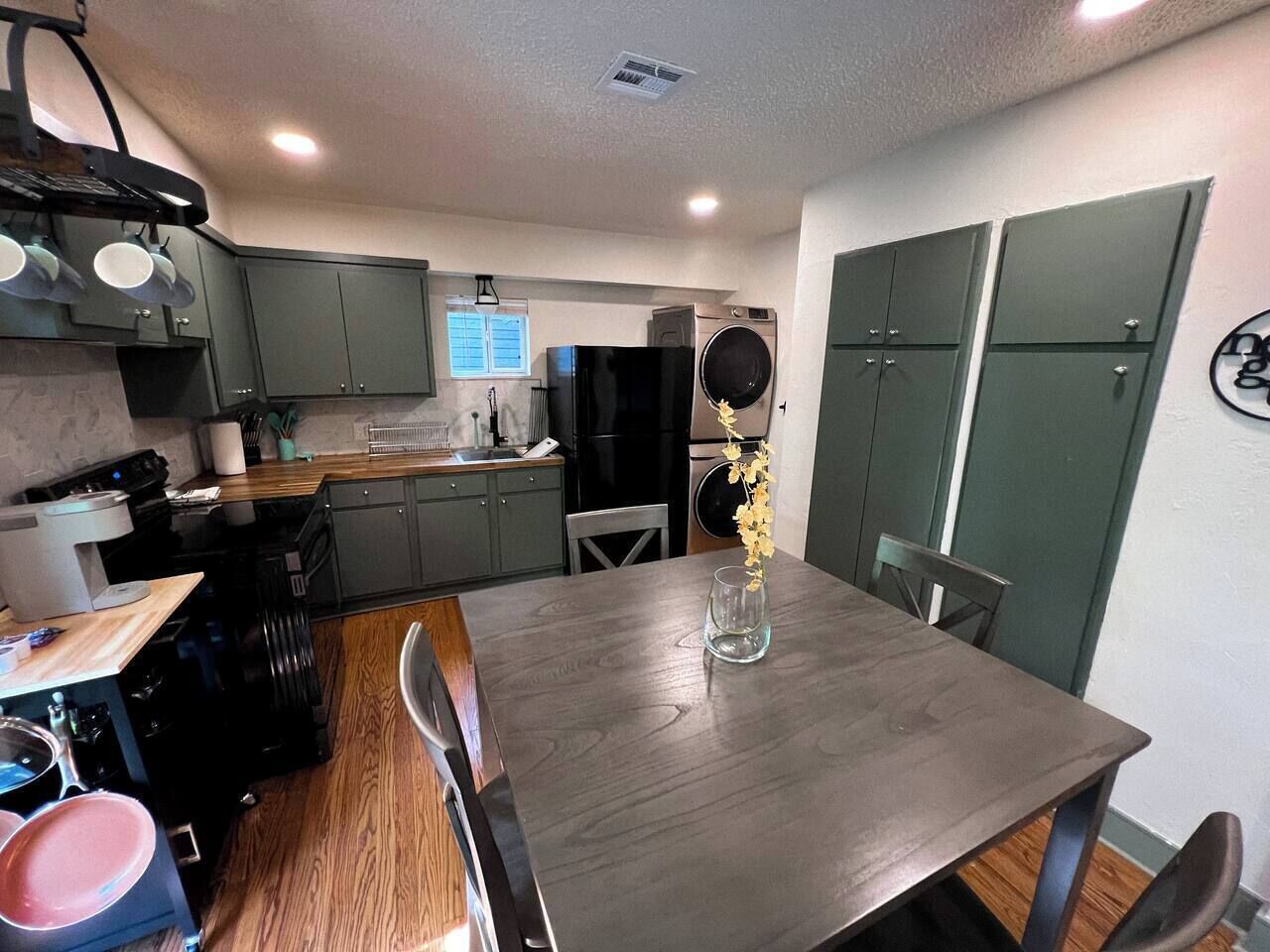 Una cocina con mesa de comedor, armarios y refrigerador.