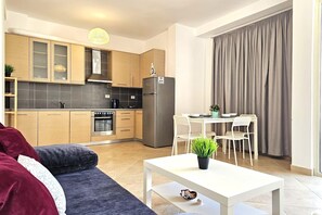 Eine moderne Küche mit Holzausstattung, einem Edelstahlkühlschrank und einem Essbereich mit weißem Tisch und Stühlen.