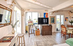 A room with a television, a painting, a dining table, and a chair. - Appartement vue panoramique (Perpignan)