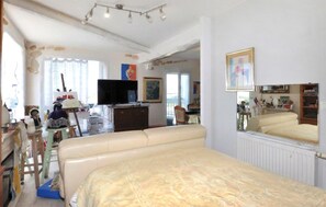 A room with a bed, a television, a dresser, and a mirror. - Appartement vue panoramique (Perpignan)