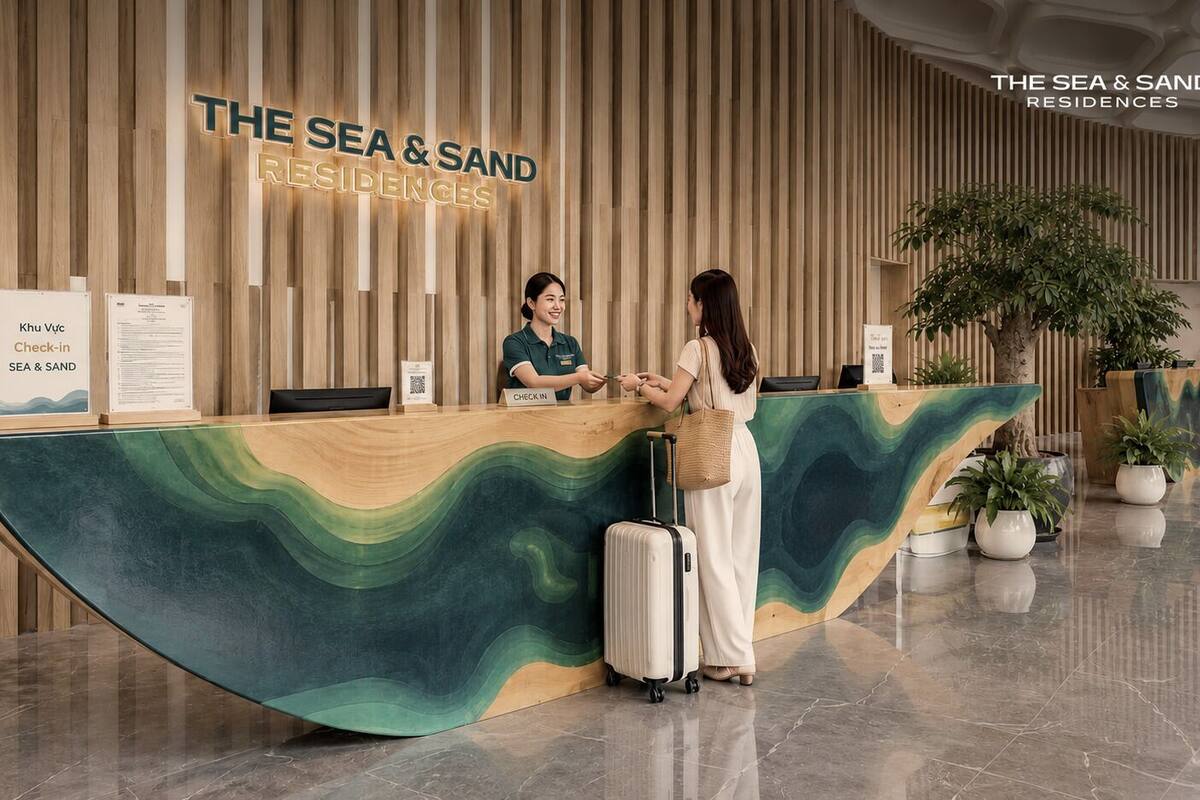 Un mostrador de recepción con diseño ondulado, una pared de madera con listones verticales y un letrero que dice 'THE SEA & SAND RESIDENCES'.