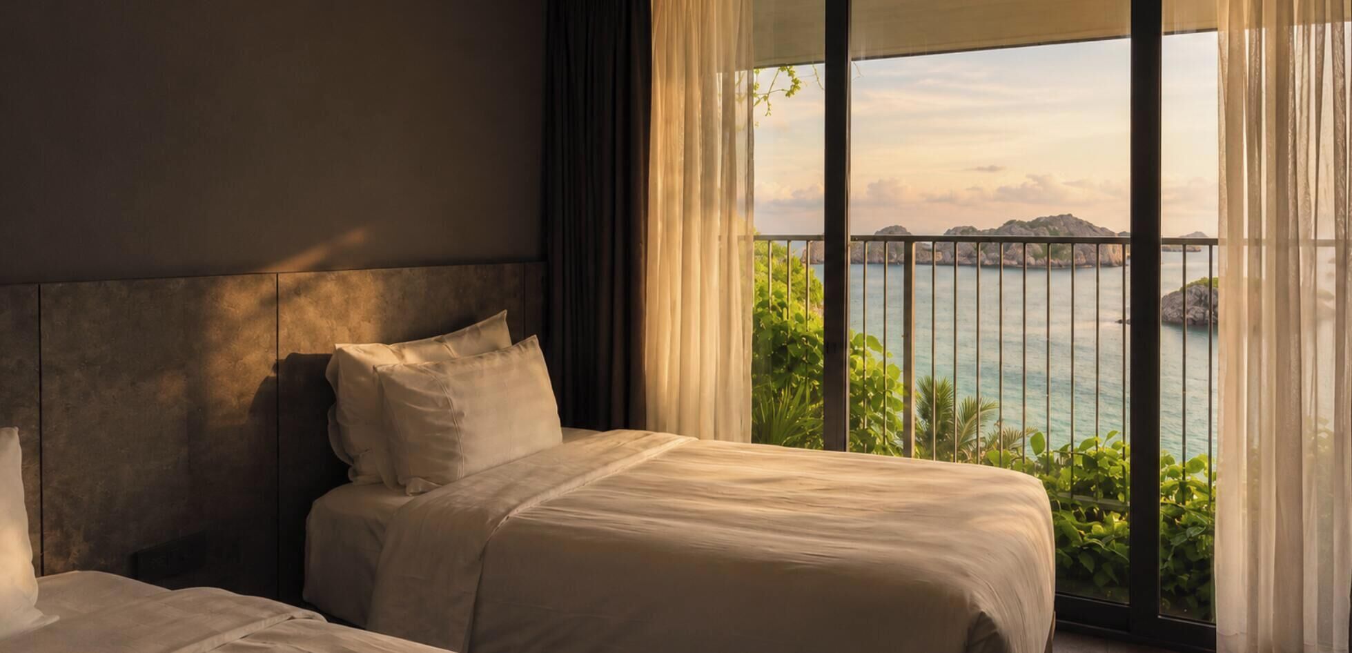 A bedroom with a large window overlooking a body of water and greenery.