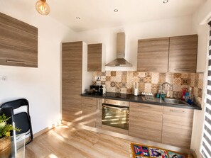 A modern kitchen with wooden cabinets, a stainless steel sink, and a patterned backsplash. - Cozy Little House Between Monaco the Beach (Cap d'Ail)