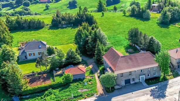 Vista aérea de una zona rural con casas rodeadas de campos verdes y árboles.