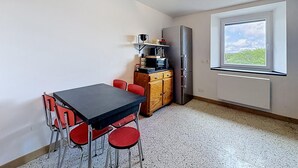 Cocina compacta con mesa y sillas, un refrigerador y una ventana con vistas.