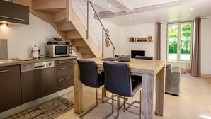 Eine moderne Küche mit einer Holztreppe, integrierten Geräten und einem Essbereich mit zwei Stühlen.