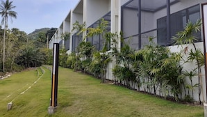 A modern building with large windows, a well-maintained lawn, and tropical plants. - 2 Bedroom Unique Indoor Pool Villa (Bophut)