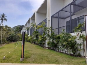 Un edificio moderno con ventanas amplias, un césped cuidado y plantas tropicales.