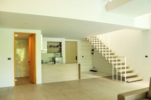 Un interior moderno con una escalera, una zona de cocina y suelo de madera.
