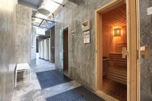 Una sala de sauna con bancos de madera, una mesita blanca y un tapete en el suelo.