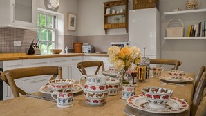 A dining table set with animal-themed tableware, a coffee pot, and a vase with flowers. - Claytons Cottage -  Cotswold Family Retreat near Stow-on-the-Wold (Lower Oddington)