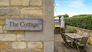 A rustic stone wall with a wooden sign reading 'The Cottage.' - Claytons Cottage -  Cotswold Family Retreat near Stow-on-the-Wold (Lower Oddington)