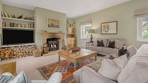 A cozy living room with a fireplace, a sofa, a coffee table, and a bookshelf. - Claytons Cottage -  Cotswold Family Retreat near Stow-on-the-Wold (Lower Oddington)
