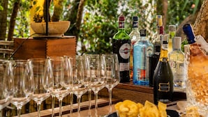 A bar area with a lamp, glasses, bottles, and snacks. - Hotel Club i Pini- Residenza d'Epoca (Camaiore)