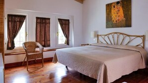 A bedroom with a bed, a chair, a painting, and a window with curtains. - Hotel Club i Pini- Residenza d'Epoca (Camaiore)