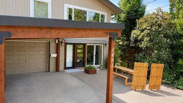 A covered patio area with a garage door, a wooden pergola, and a bench.