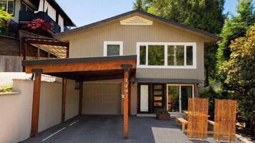 Une maison à deux étages avec un garage, un patio couvert et une cour arrière clôturée.