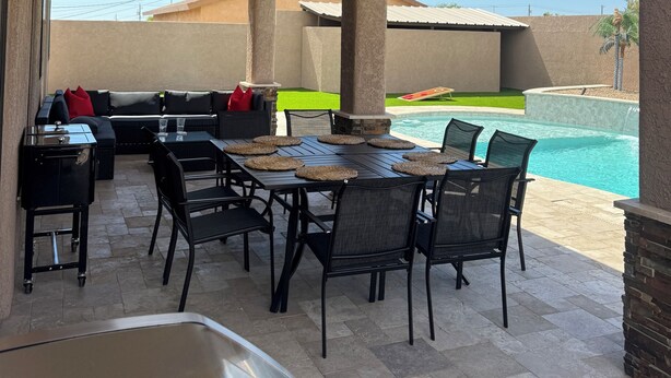 Un patio exterior con piscina, mobiliario cubierto y ventilador de techo.
