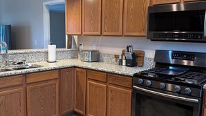 Una cocina moderna con armarios de madera, un microondas de acero inoxidable, una estufa a gas y un horno empotrado.