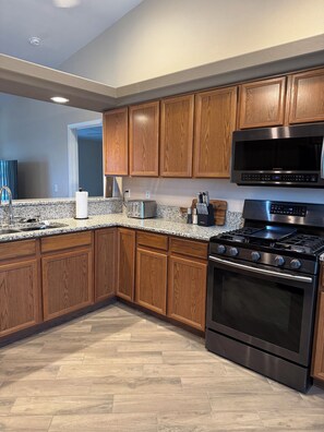 A modern kitchen with wooden cabinets, a stainless steel microwave, a gas stove, and a built-in oven. - Pool & Spa - Boat Parking - 1 Mile to Downtown (Lake Havasu City)