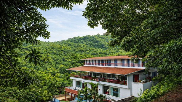 Un edificio a due piani con piscina, immerso nel verde.