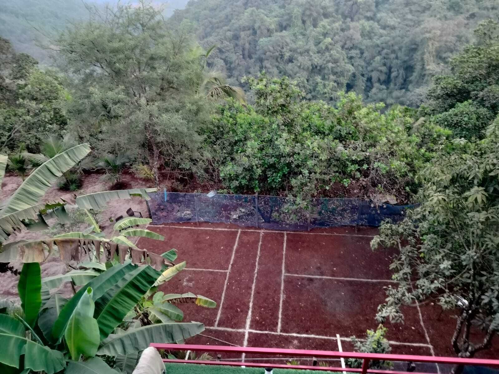 En tennisbane omgivet af frodig vegetation og bakker.