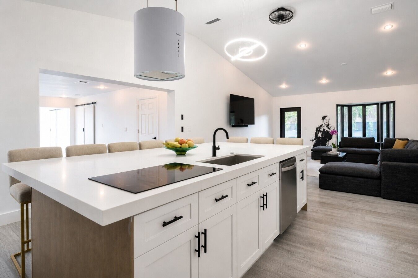 A modern kitchen with a central island, white cabinetry, and a dining area with chairs.
