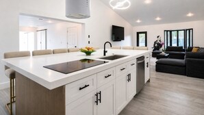 Une cuisine moderne dotée d’un îlot central, de meubles blancs et d’un coin repas avec des chaises.