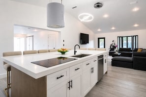 Una cocina moderna con una isla central, muebles blancos y una zona de comedor con sillas.