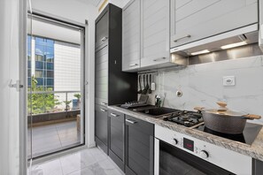 A modern kitchen with a gas stove, a range hood, and a view through a sliding door to an outdoor balcony. - Smart Stay Lugano, Lugano, Switzerland (Lugano)