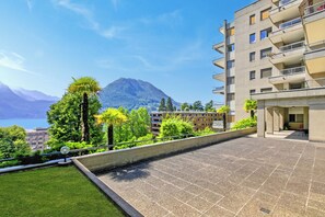 Terraza en la azotea con vistas a una montaña y un lago, rodeada de vegetaci ón y un edificio moderno.