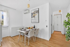 Ein moderner Essbereich mit einem weißen Tisch, Stühlen und einem großen, abstrakten Gem älde an der Wand.