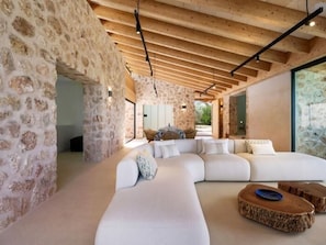 Ein modernes Interieur mit Steinwänden, Holzbalkendecke und einem großen weißen Sofa.