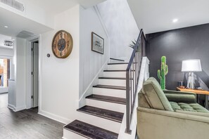 A staircase with a dark wood finish, a green cushioned bench, a cactus decoration, and a framed picture on the wall. - Stylish Dallas Escape - 3 Min to Love Field (Dallas)