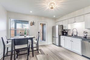 Eine moderne Küche mit weißen Schränken, einem Edelstahlkühlschrank und einem Essbereich mit Tisch und Stühlen.