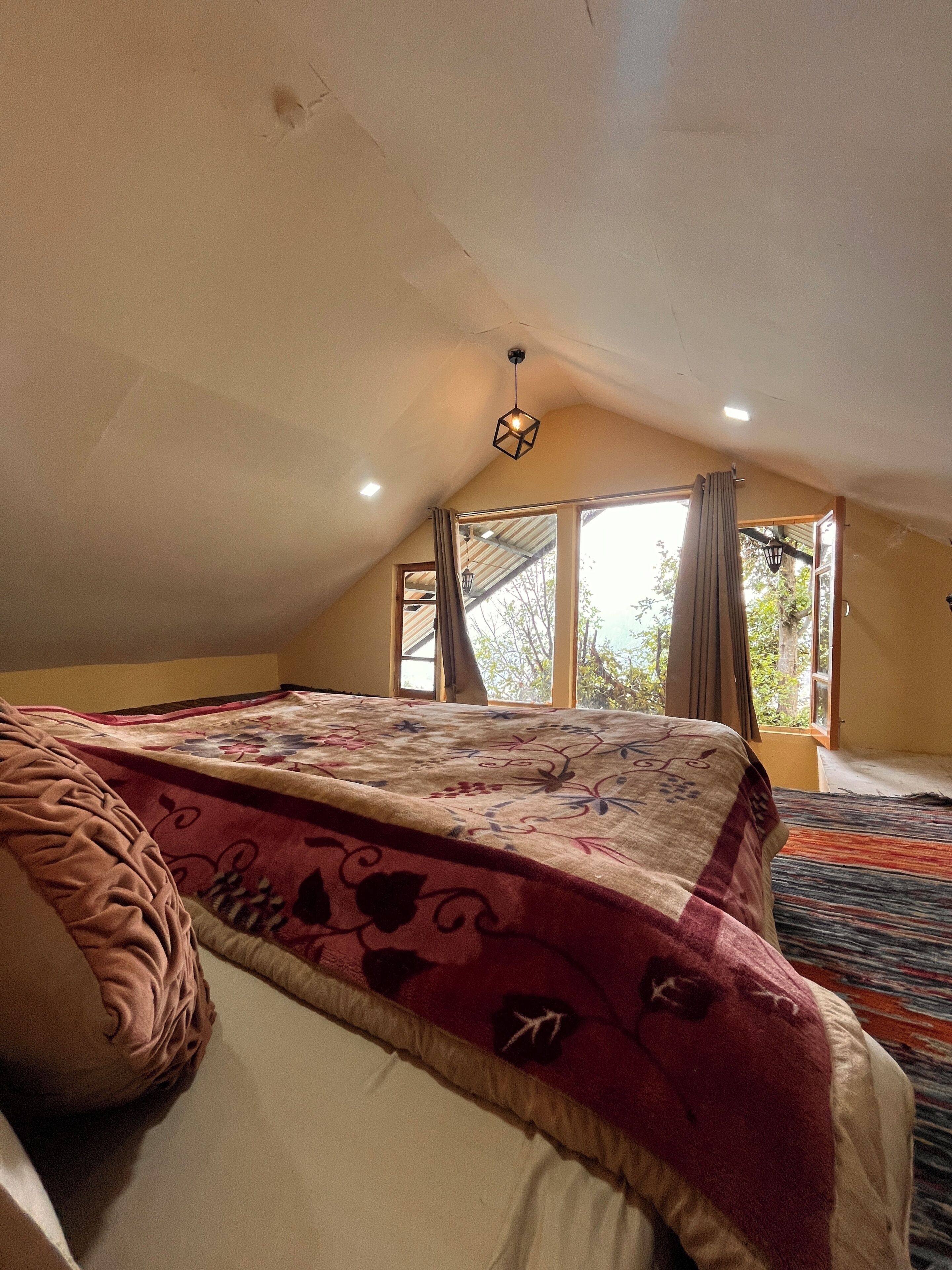 An attic bedroom with a large bed, a window with curtains, and a sloped ceiling.