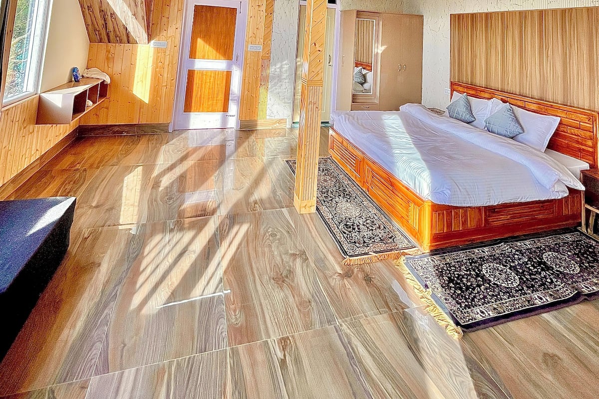 Un interior de madera con una cama, un banco y una puerta.