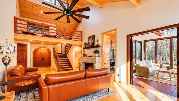 Un vaste espace de vie doté d’un haut plafond, d’un escalier en bois, d’une cheminée et d’un balcon avec coin salon extérieur.