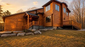 Une cabane en rondins dotée d’une véranda, d’un escalier et de fondations en pierre.