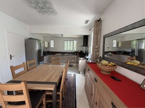 Eine moderne Küche mit Edelstahlgeräten, einem Essbereich mit Holzmöbeln und einem großen Spiegel über der Arbeitsfläche.